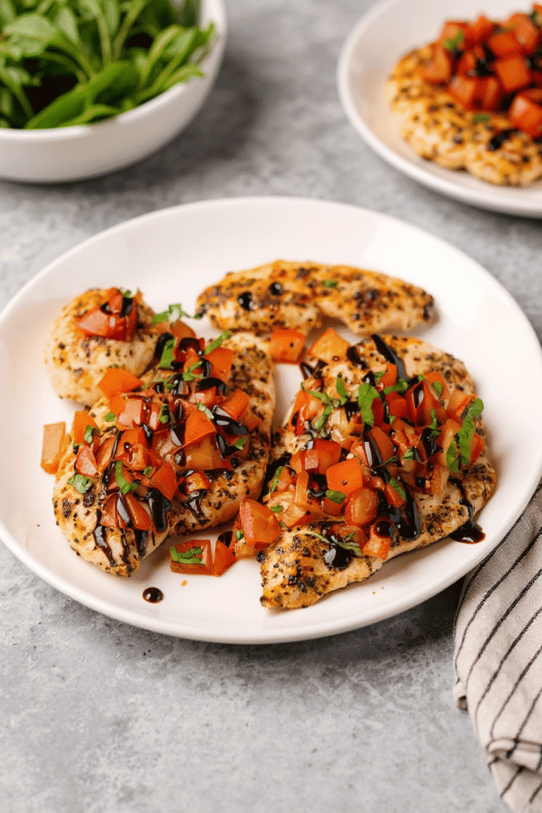 Grilled chicken topped with fresh tomato salsa and balsamic glaze on a white plate for a healthy recipe.